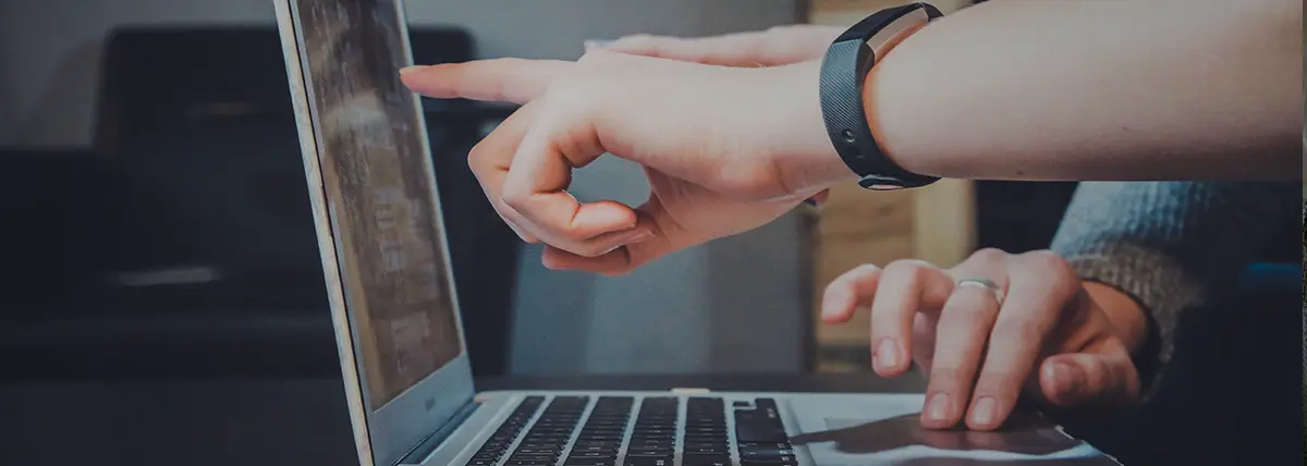 a hand pointing out something on a laptop monitor
