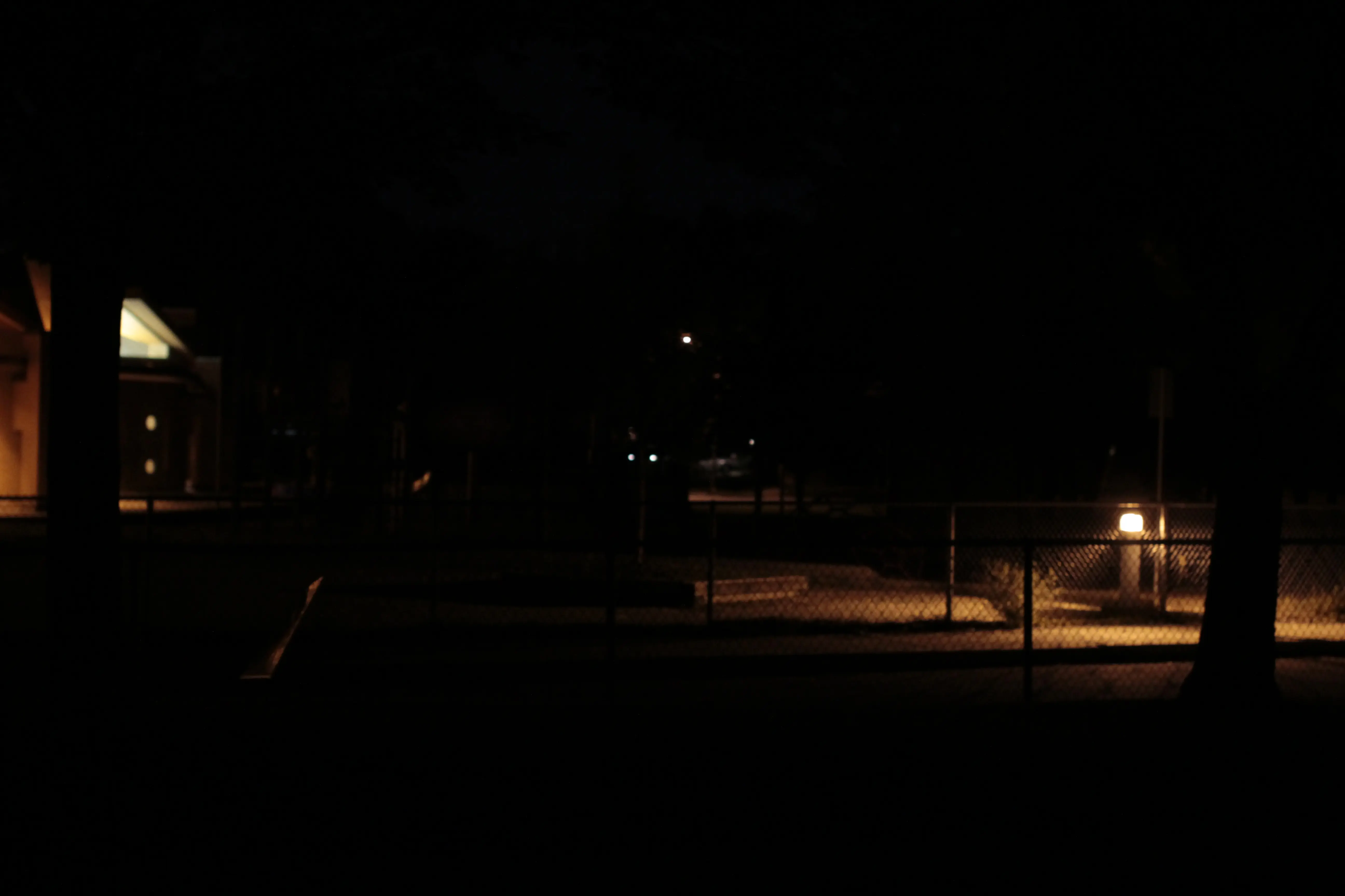 image a park taken at night withough night vision enhancement, not much is visible due to a lack of light